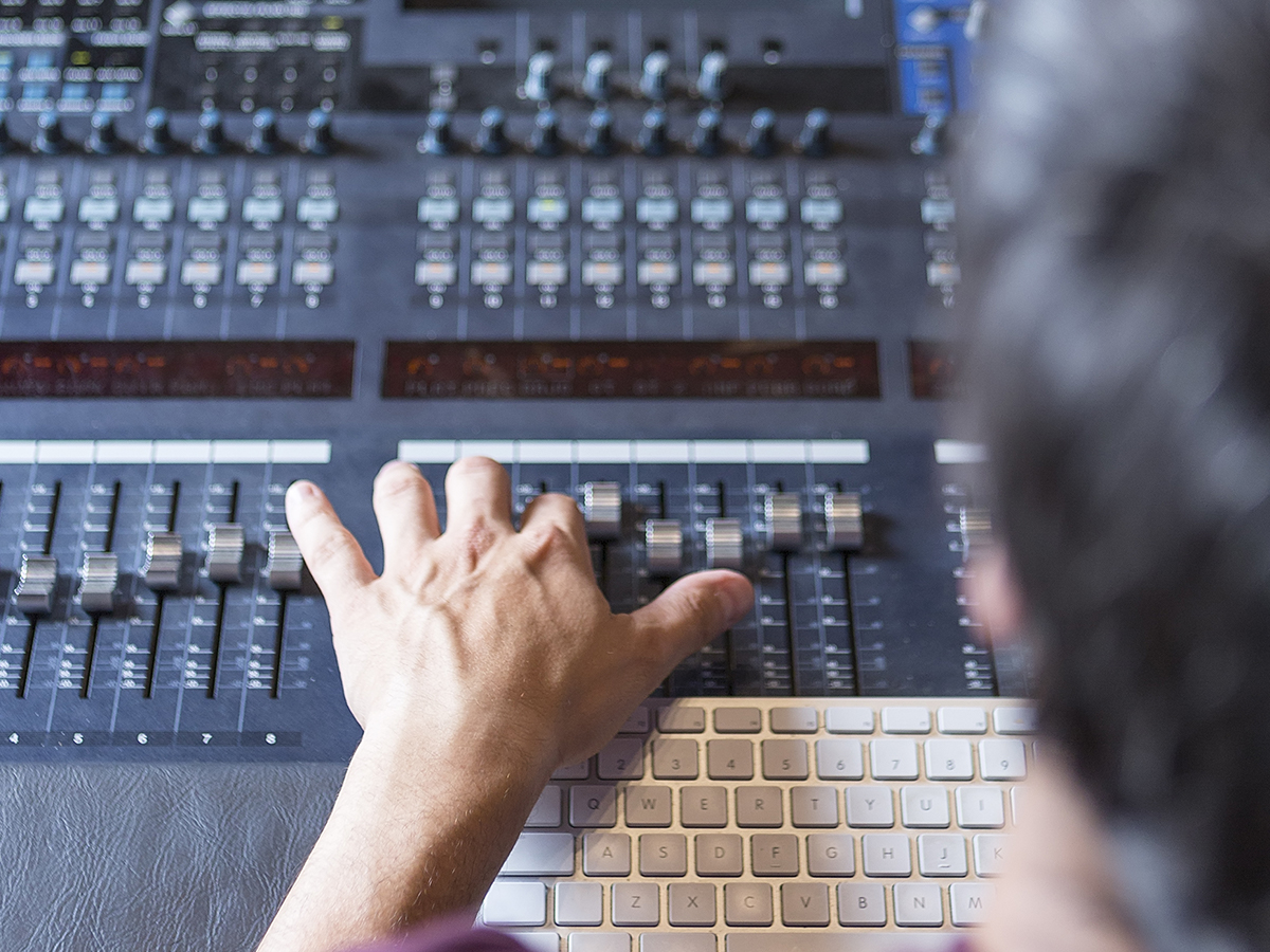 Image of an audio engineer mastering a music track in a recording studio.